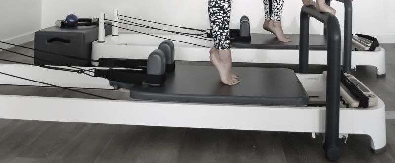 A woman using a pilates reformer.