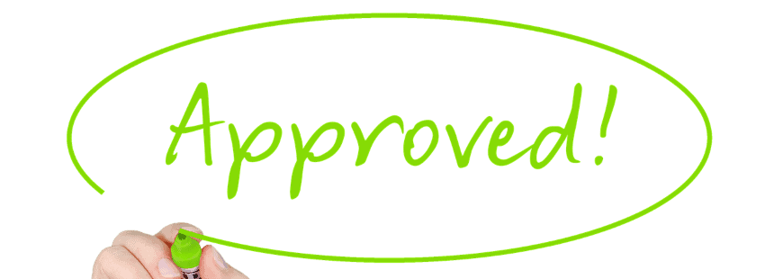 A man writing approved on a wall.