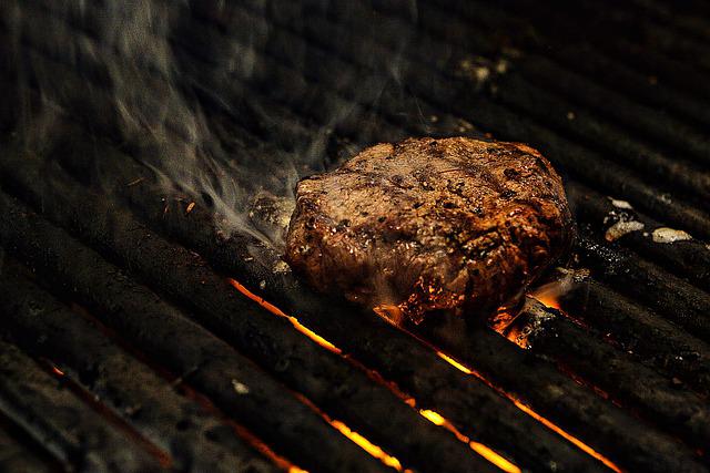 A pellet grill cooking a steak.