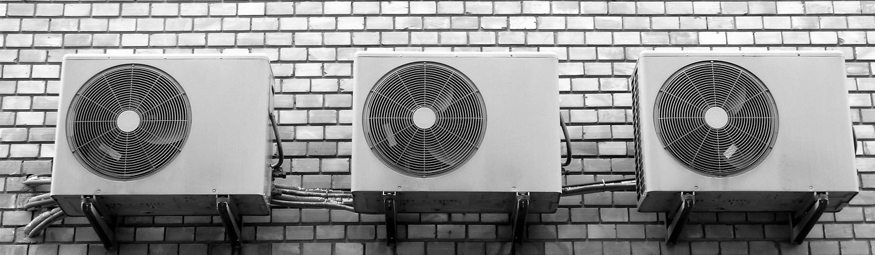 Several air conditioners mounted on a wall.